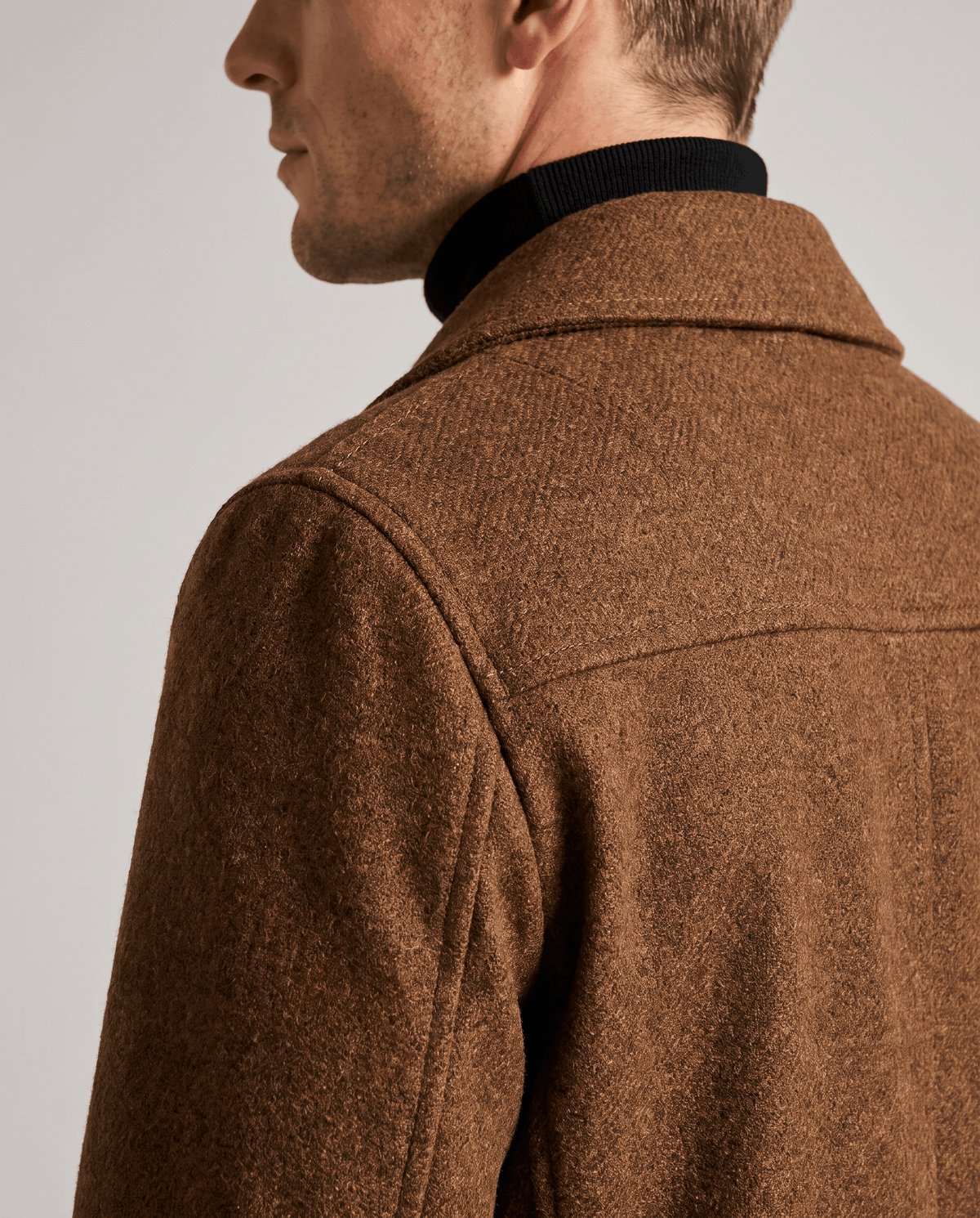 Close-up of a brown classic double-breasted trench coat, showing the structured collar and tailored shoulder detail