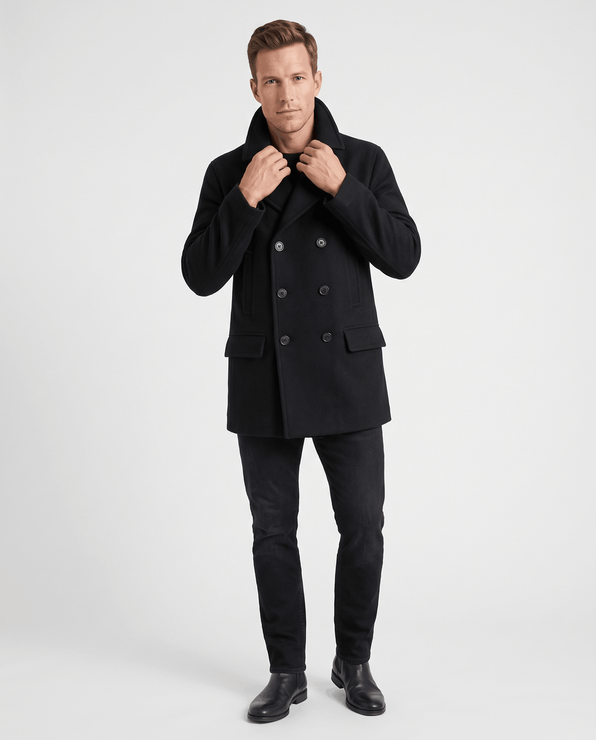 A man wearing a black classic double-breasted trench coat with a longline fit and tailored lapels