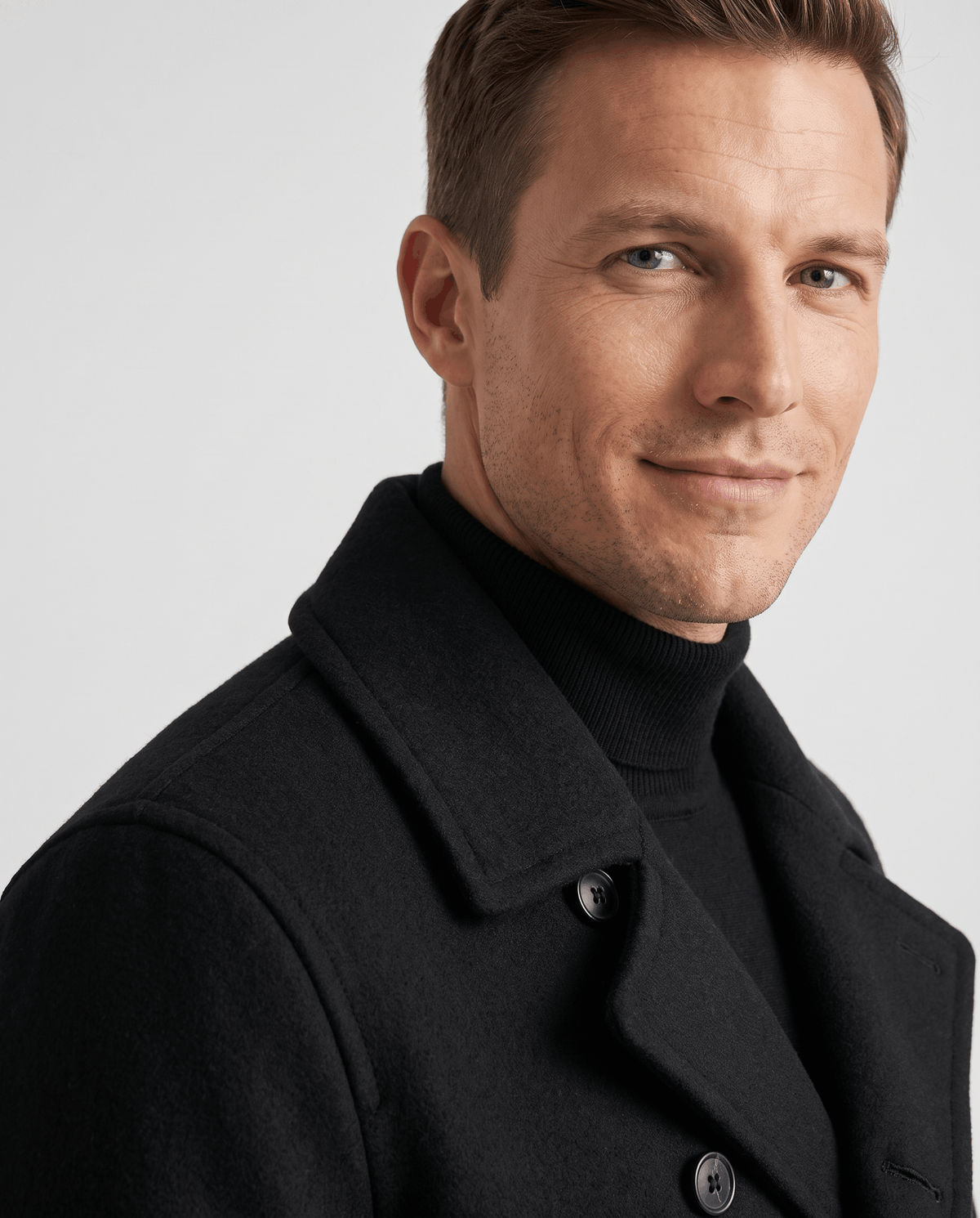 Close-up of a black classic double-breasted trench coat, showing the structured collar and tailored shoulder detail