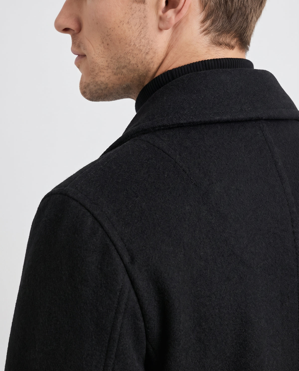 Close-up of a black classic double-breasted trench coat, showing the structured collar and tailored shoulder detail