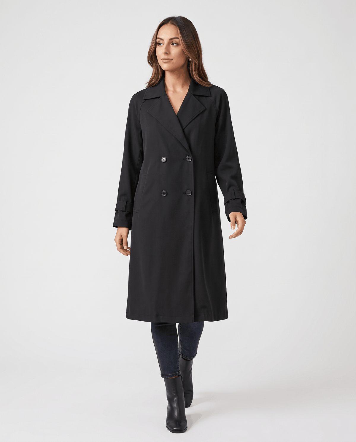 A woman wearing a black classic trench coat with a lapel collar and double-breasted button closure, front view