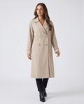 A woman wearing a beige classic trench coat with a lapel collar and double-breasted button closure