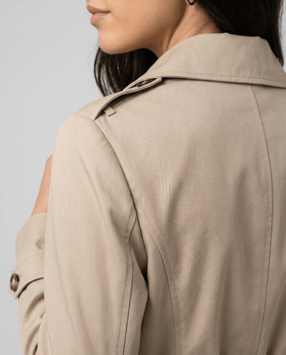 Close-up of a woman wearing a cream classic trench coat, showing the lapel collar and back detail