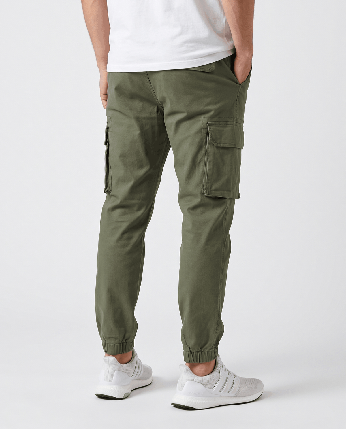 A man wearing olive green cotton cargo jogger pants with a tapered fit and utility pockets, shown from the back