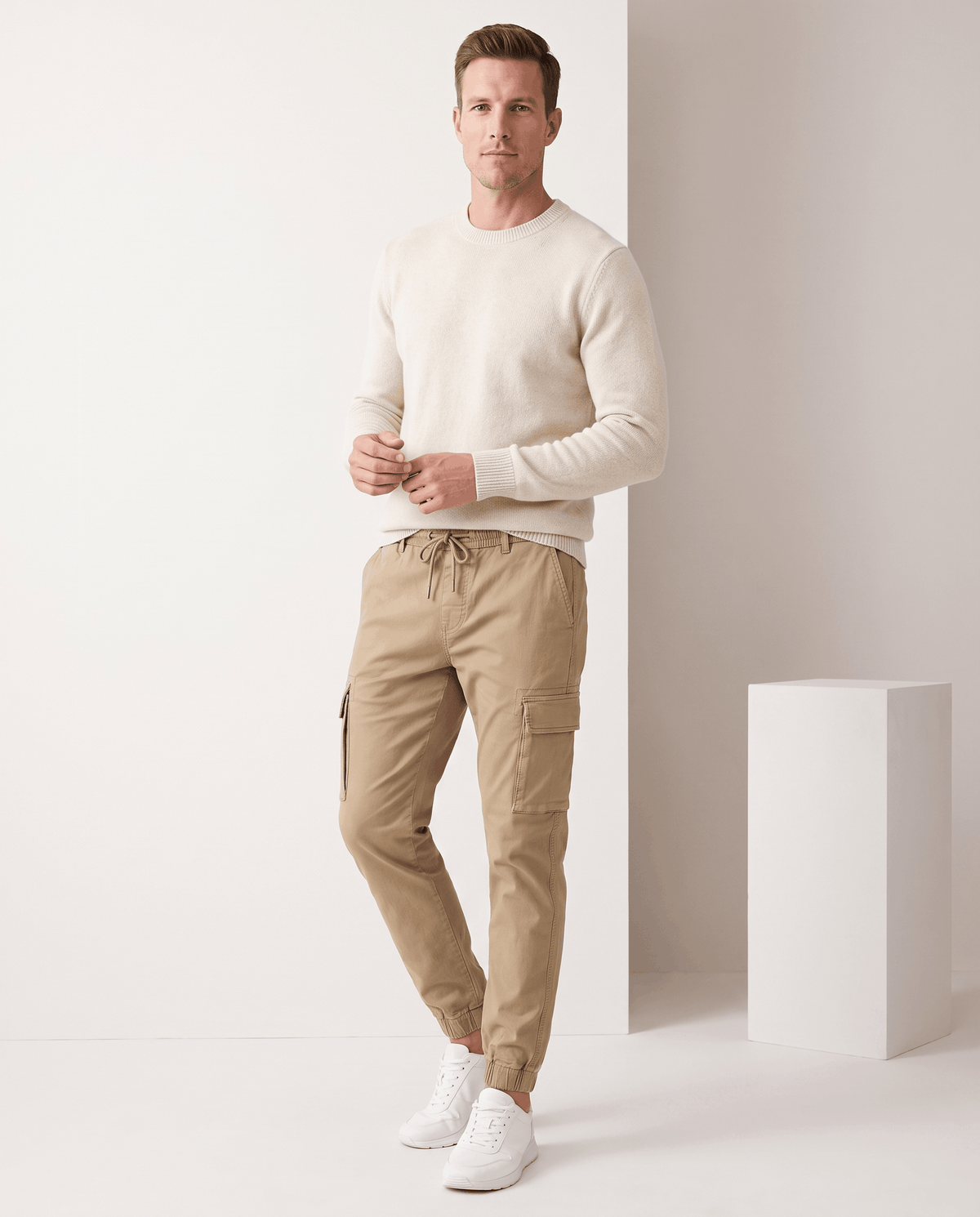 A man wearing khaki cotton cargo jogger pants with a tapered fit and utility pockets, standing indoors