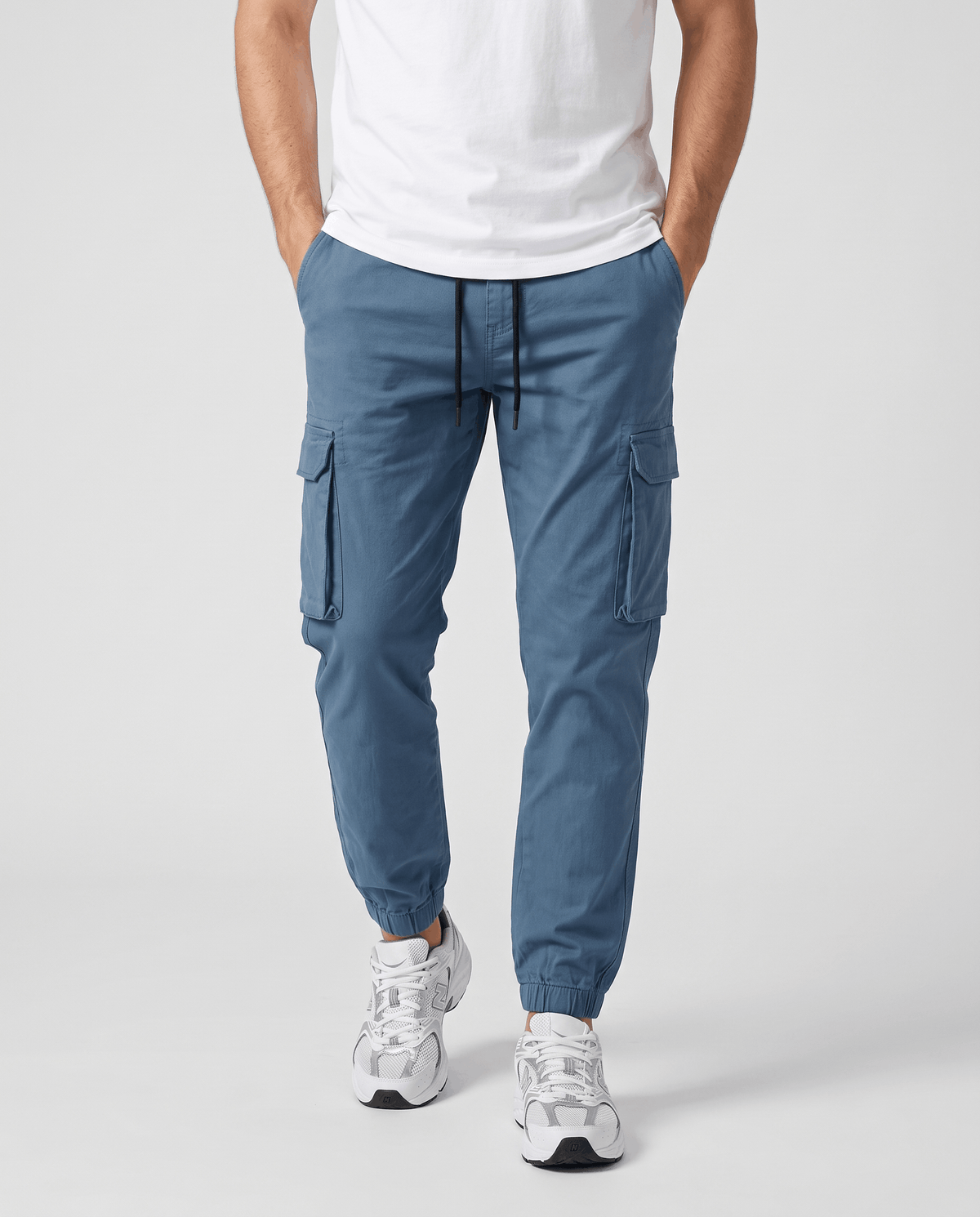 A man wearing blue cotton cargo jogger pants with a tapered fit and utility pockets, shown from the front