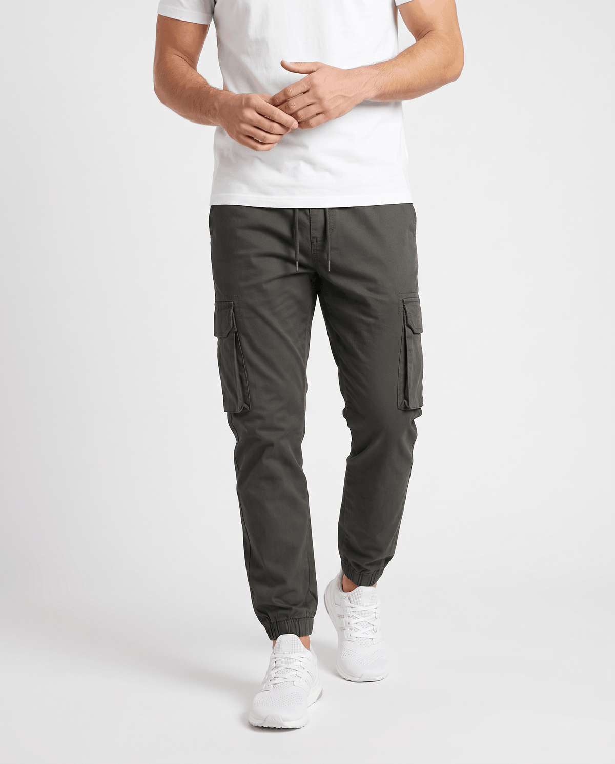A man wearing dark gray cotton cargo jogger pants with a tapered fit and utility pockets, front view