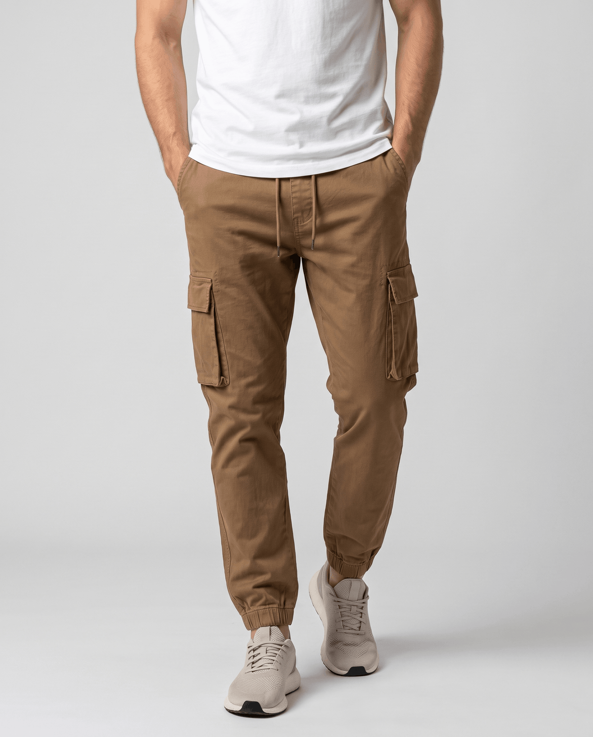 A man wearing brown cotton cargo jogger pants with a tapered fit and utility pockets, shown from the front