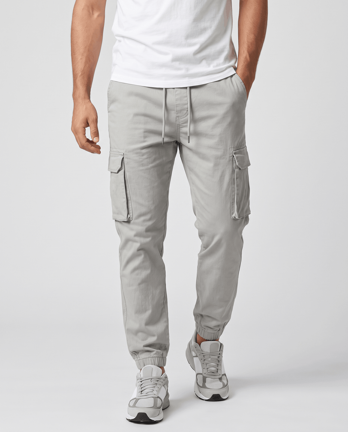 A man wearing light gray cotton cargo jogger pants with a tapered fit and utility pockets