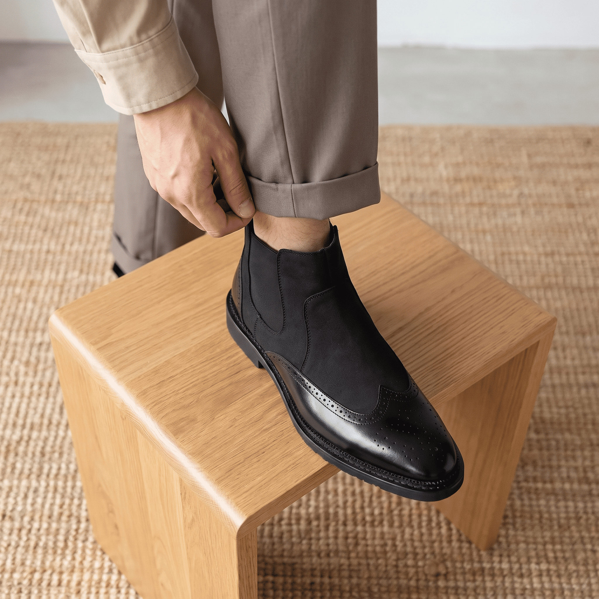 Close-up of a person wearing black Chelsea boots while seated, showing the side profile and sole.