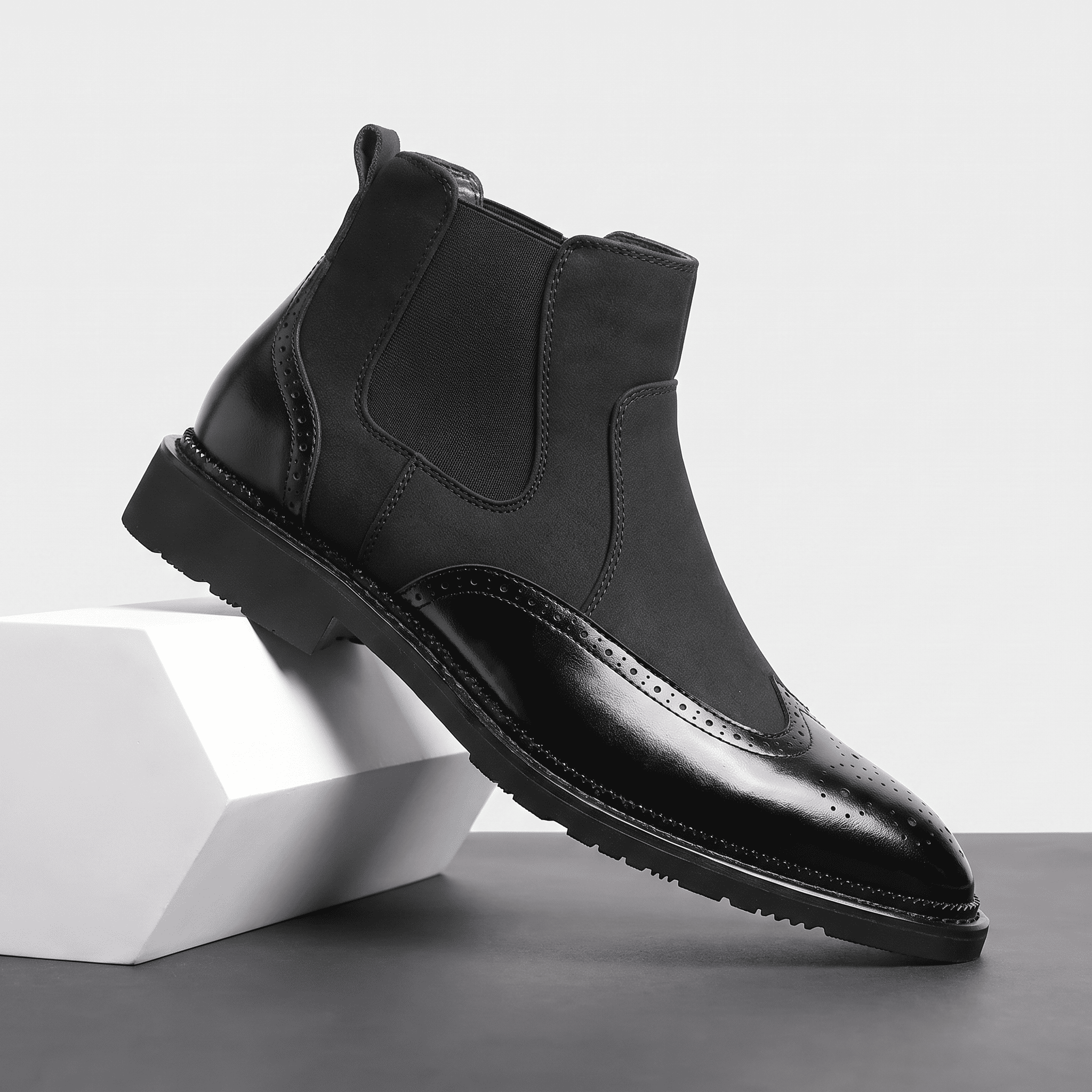 Single black leather Chelsea boot displayed on a white pedestal, featuring an elastic side panel, pull tab, and rugged rubber sole.
