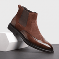 Brown leather Chelsea boot with dark elastic side panels, rear pull tab, stitched detailing, polished toe, and rugged rubber sole.
