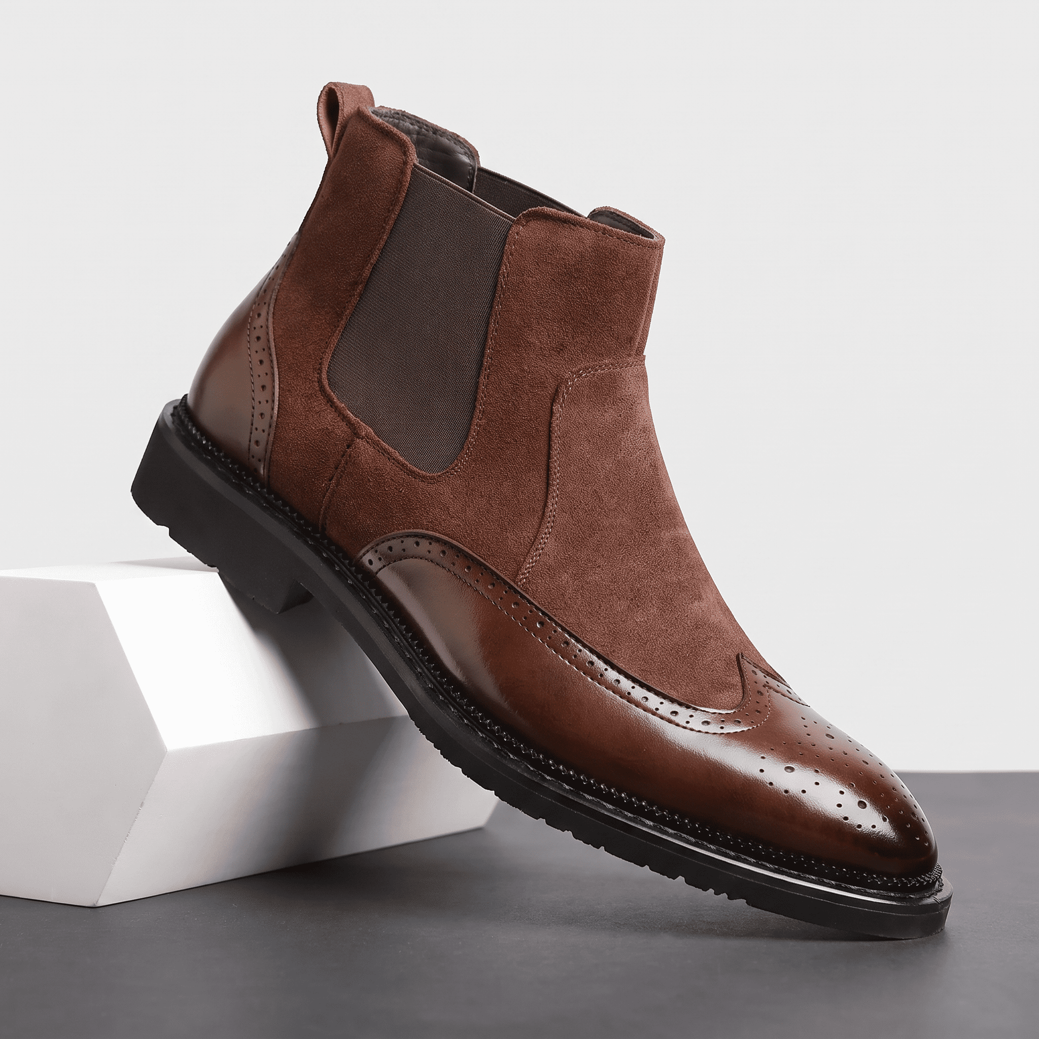 Brown leather Chelsea boot with dark elastic side panels, rear pull tab, stitched detailing, polished toe, and rugged rubber sole.