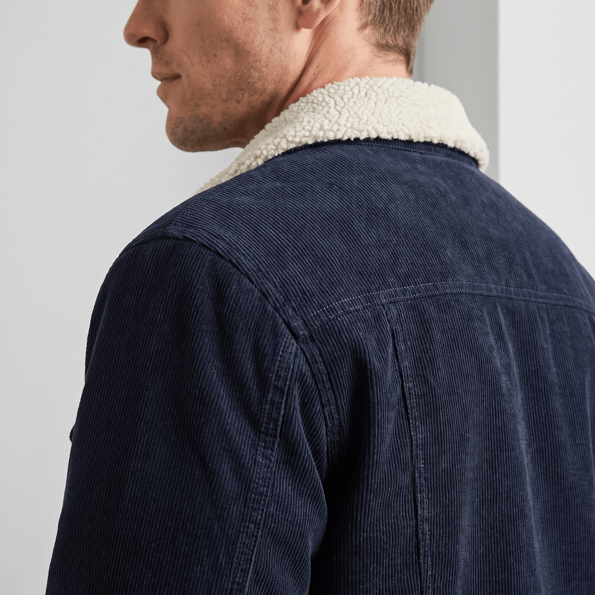Navy blue corduroy jacket featuring a cream-colored sherpa-lined collar and a structured, tailored fit.