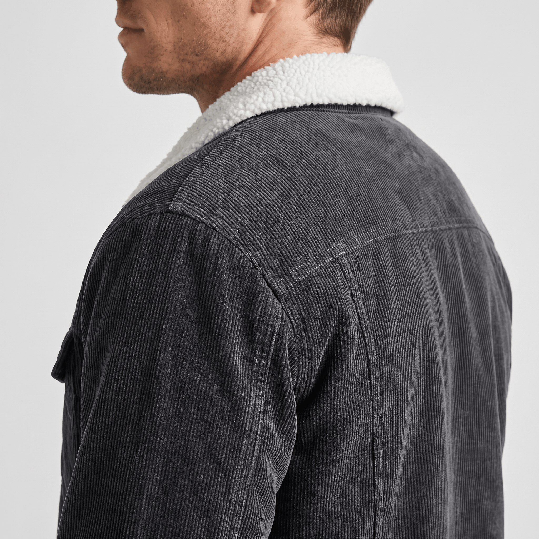 Charcoal grey corduroy jacket with a plush white sherpa collar and lining, shown from a side profile view.