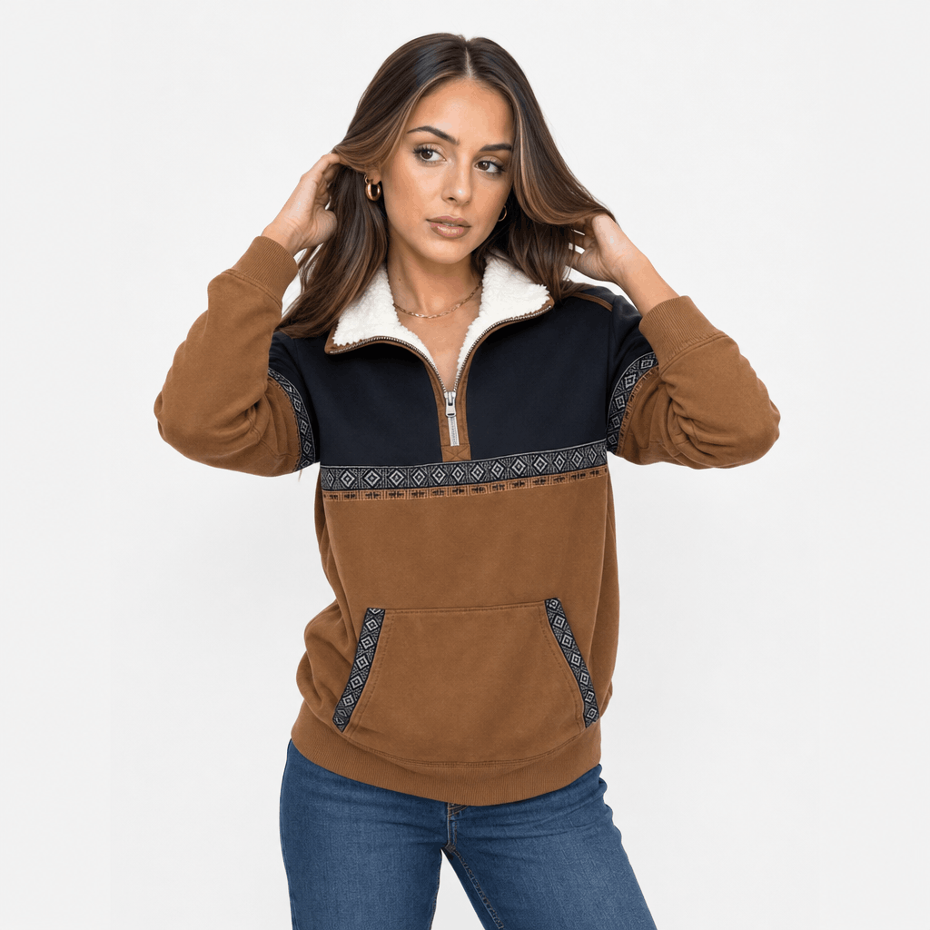 Woman wearing a color-block half-zip pullover with a navy upper panel, brown sleeves and lower body, and blue jeans, shown adjusting the collar.