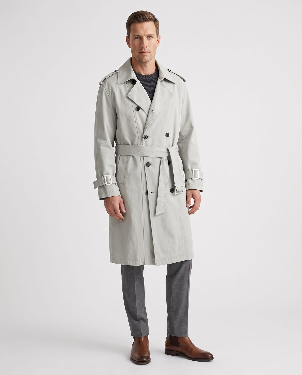 A man wearing a light gray double-breasted trench coat with a belted waist and adjustable cuffs