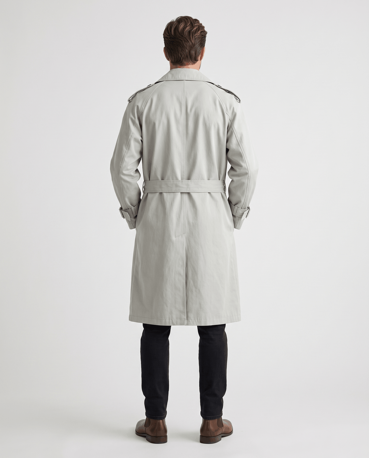A man wearing a light gray double-breasted trench coat with a belted waist and adjustable cuffs, shown from the back