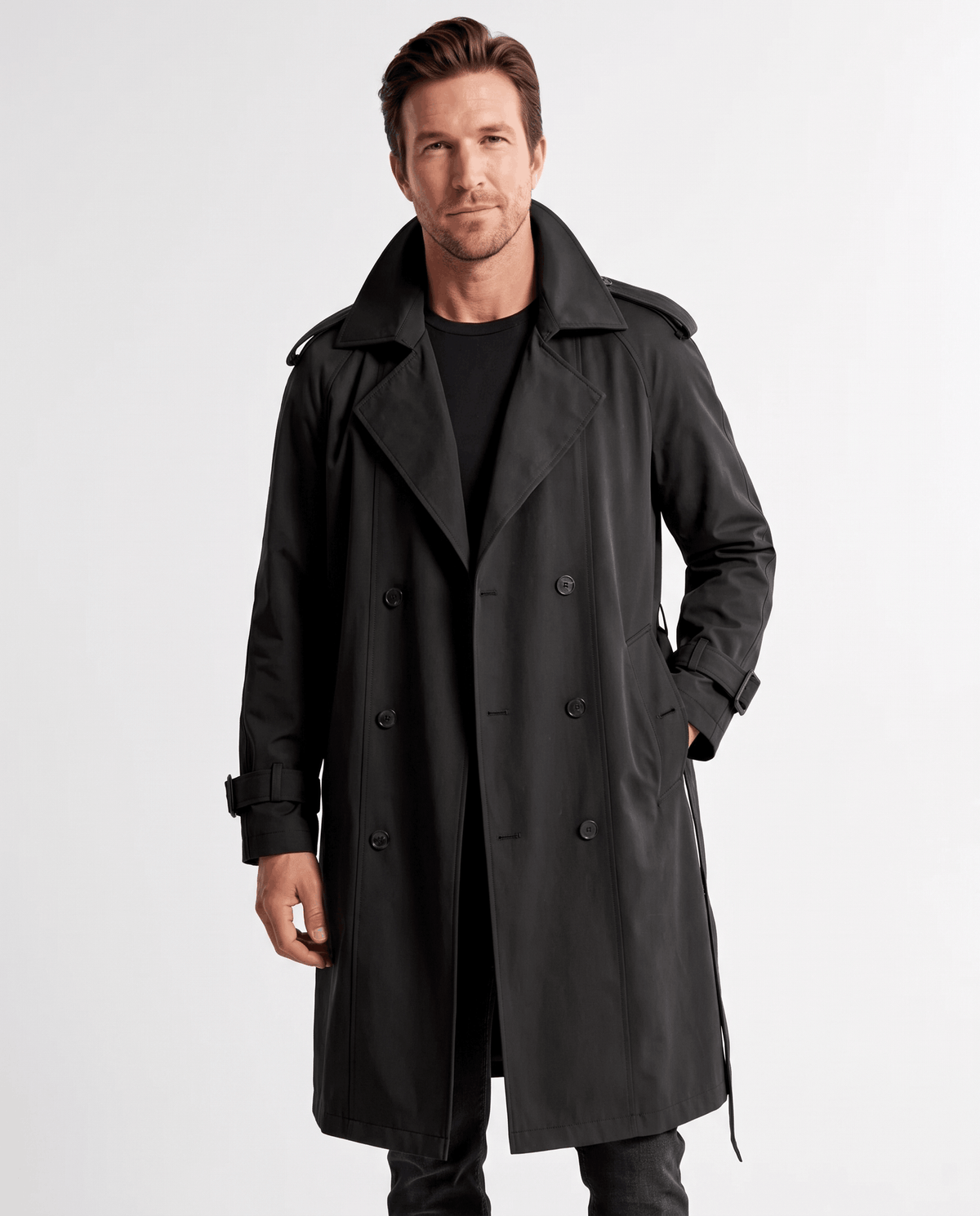 Black double-breasted trench coat with wide lapels, shoulder epaulettes, and cuff straps worn by a male model