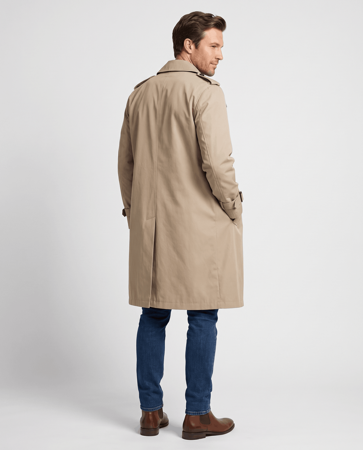 A man wearing a beige double-breasted trench coat with a belted waist and adjustable cuffs, shown from the back