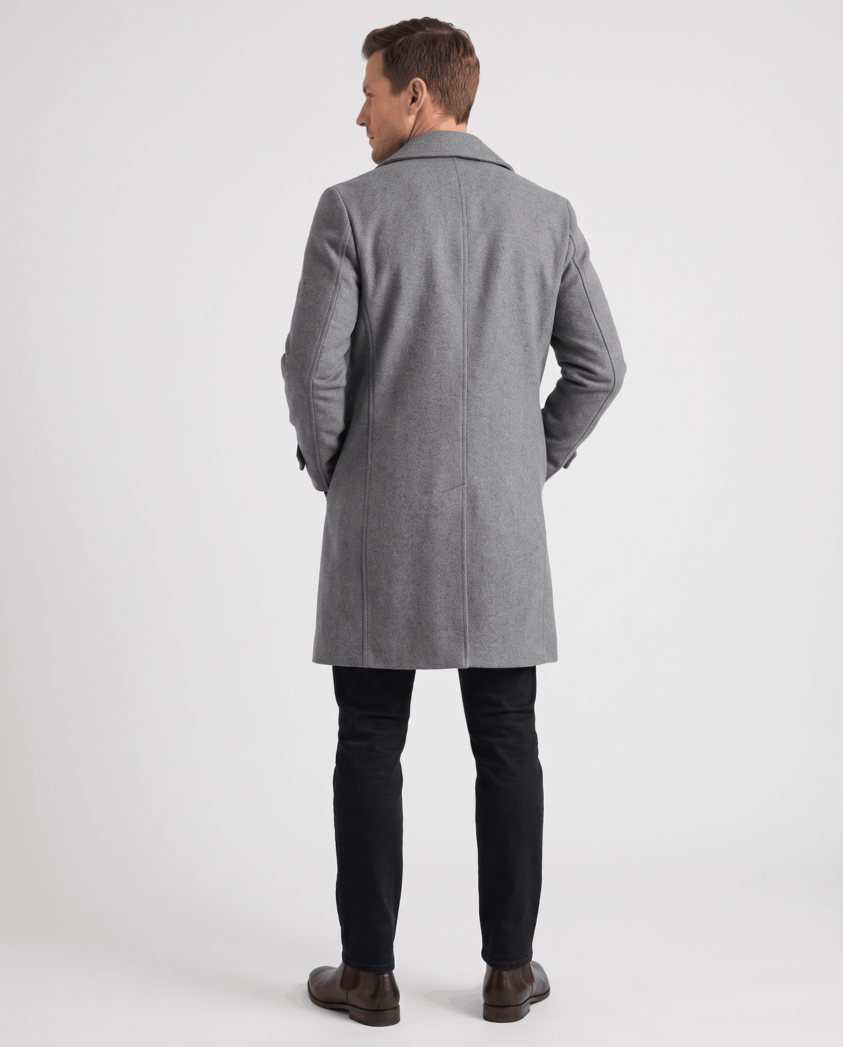 A man wearing a gray double-breasted trench coat with a longline fit and structured shoulders, back view