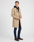 A man wearing a black double-breasted trench coat with a mid-length fit, walking outdoors on a city street