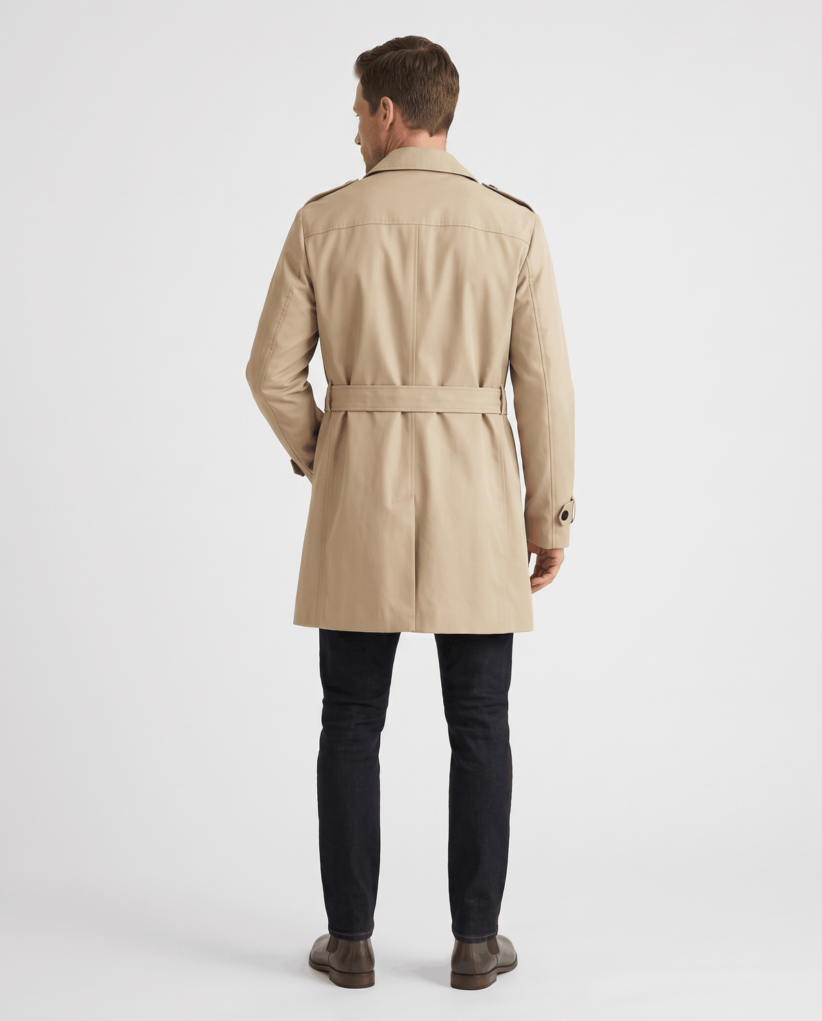 A man wearing a beige double-breasted trench coat with a mid-length fit, shown from the back with adjustable cuffs