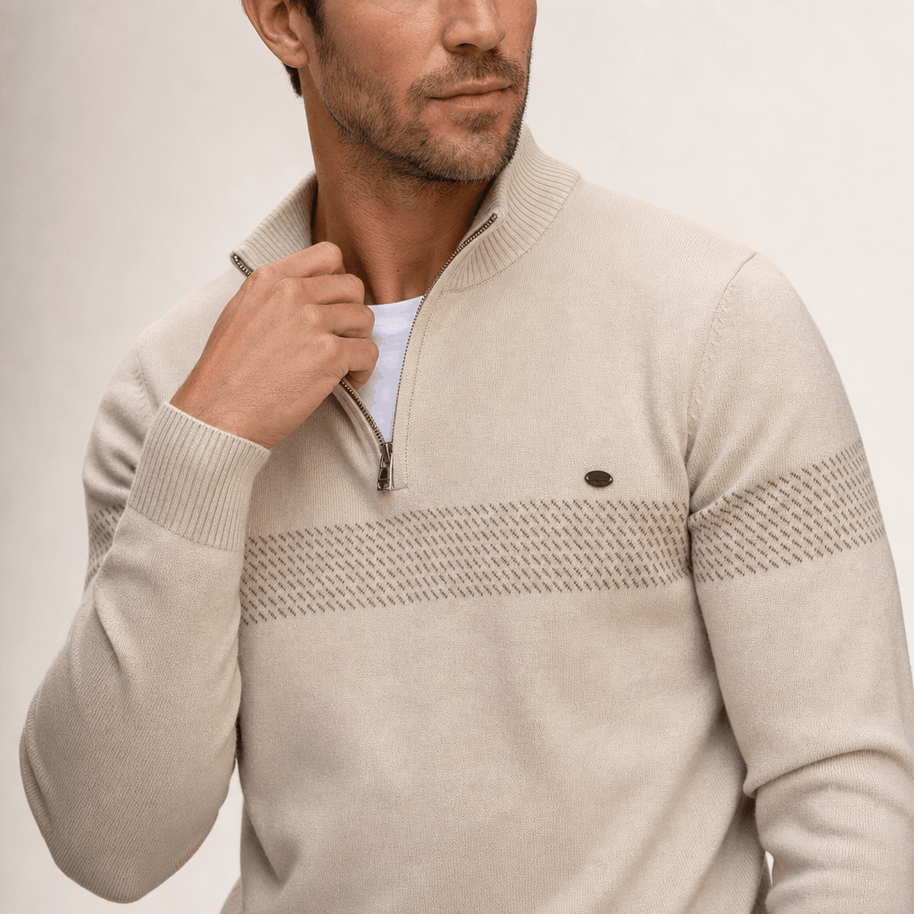 Close-up of the beige quarter-zip sweater, highlighting the raised collar, zipper, textured chest stripe, and small chest detail.