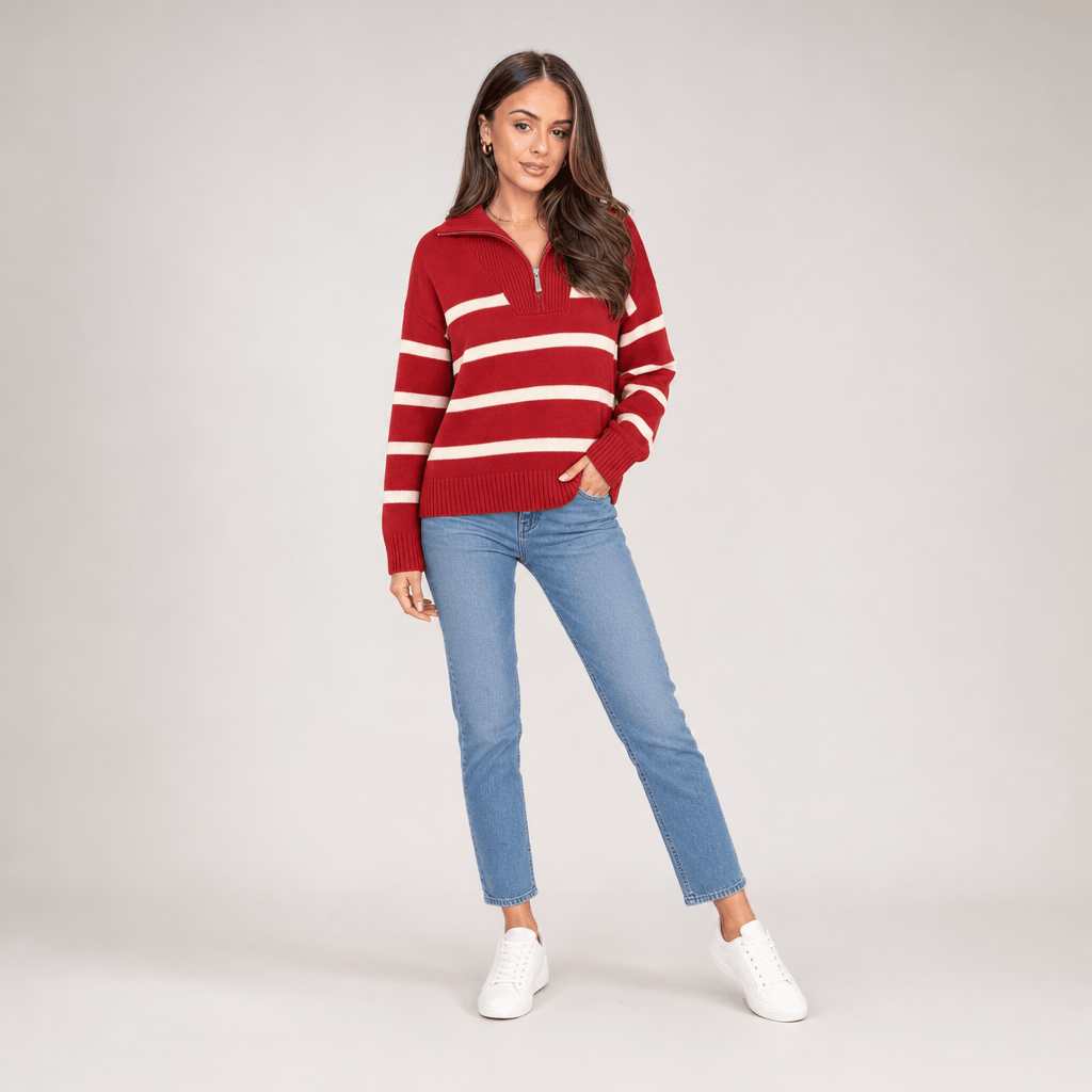 Full-body view of a female model wearing the red and white striped quarter-zip sweater with blue jeans.