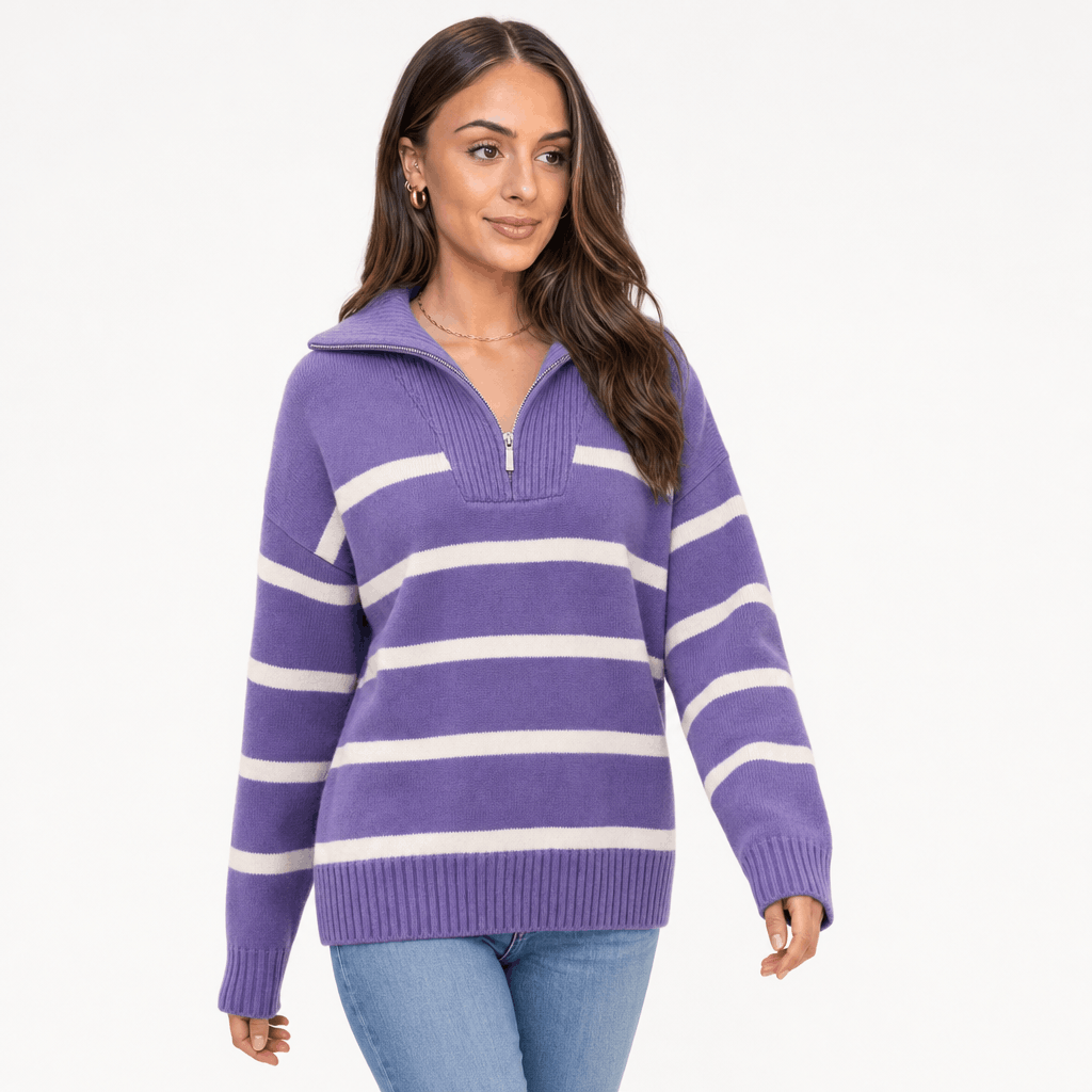 Female model wearing a purple quarter-zip sweater with white horizontal stripes, paired with blue jeans.