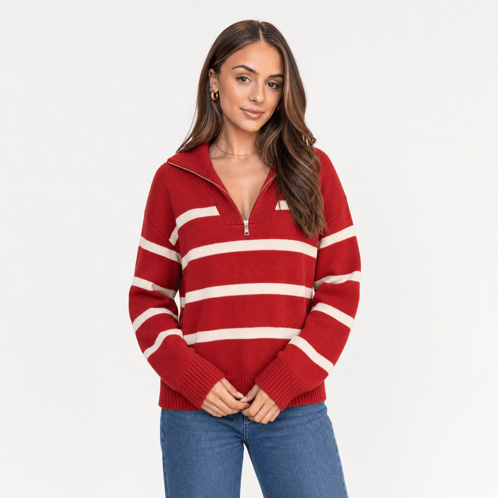 Female model wearing a red quarter-zip sweater with white horizontal stripes, paired with blue jeans.