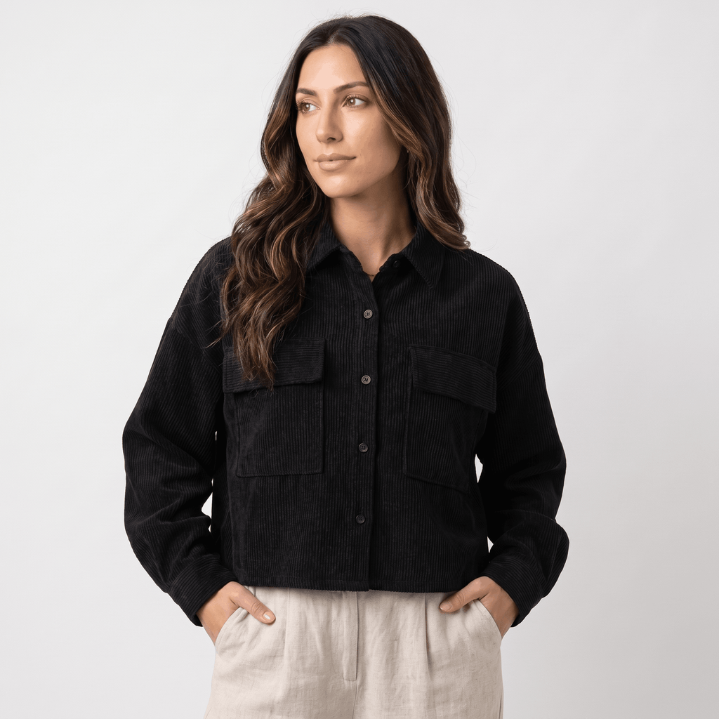 Black corduroy overshirt with a relaxed drop-shoulder fit, button-front closure, and dual chest pockets.