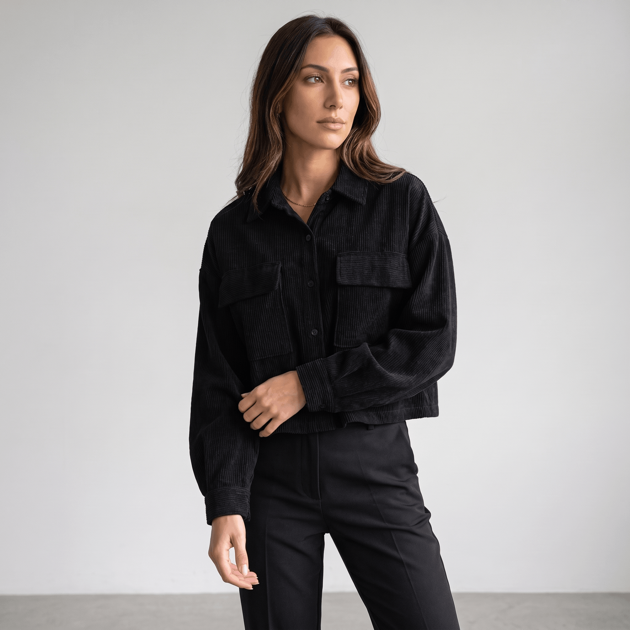 Black corduroy overshirt with a relaxed drop-shoulder fit, button-front closure, and dual chest pockets.