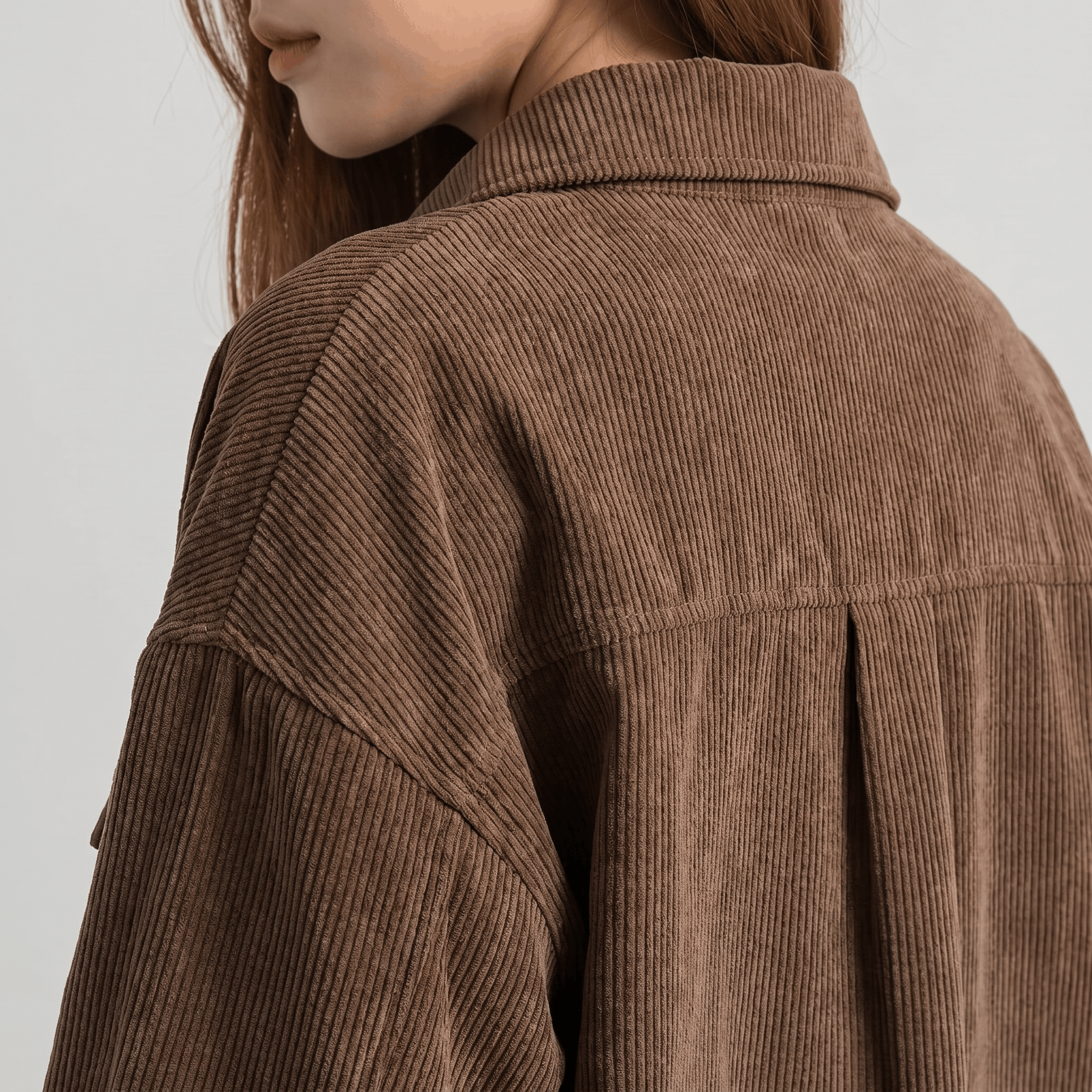 Muted brown corduroy overshirt featuring a relaxed drop-shoulder silhouette and a structured back yoke pleat.