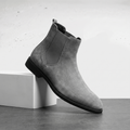 Gray Chelsea boot with elastic side panels, a rear pull tab, smooth suede-style upper, and low stacked sole.