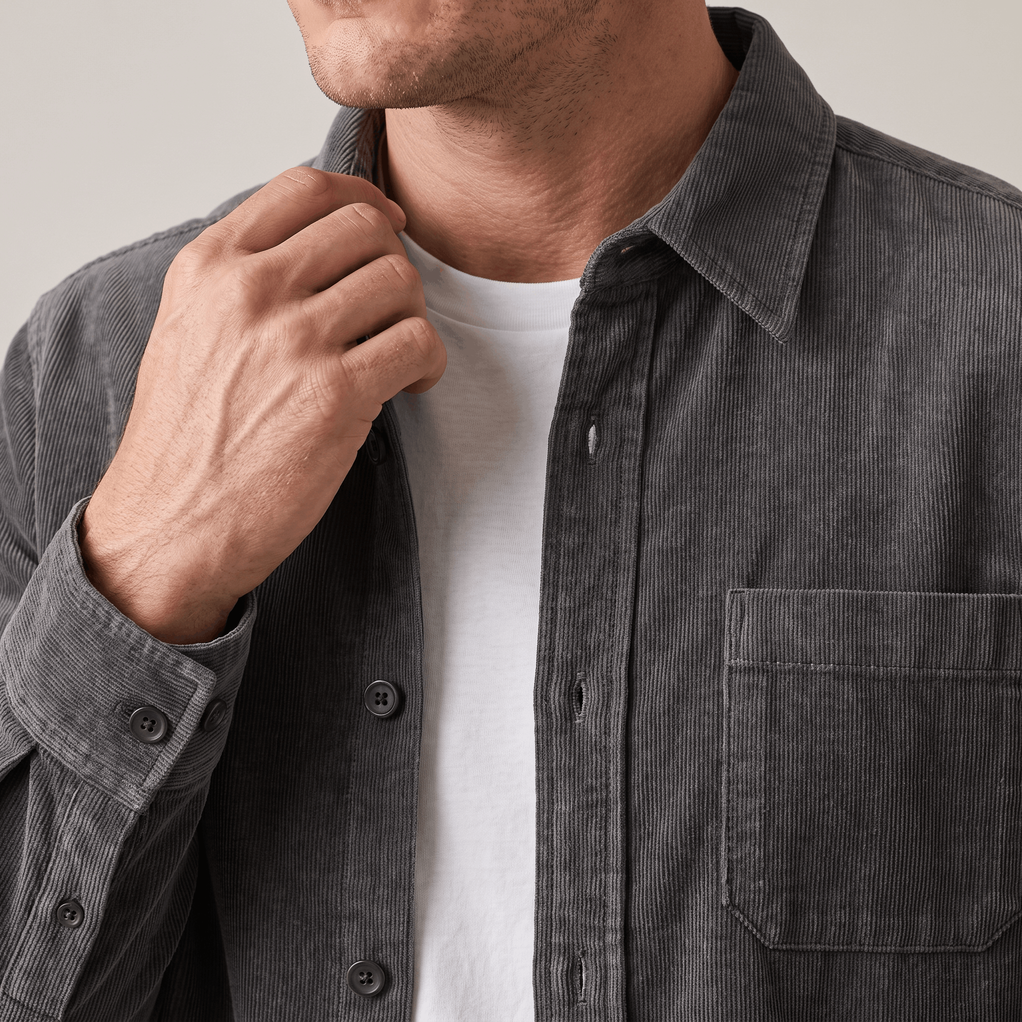 Charcoal grey washed corduroy button-up shirt with a single chest pocket, worn open over a white tee.