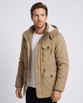 A man wearing a beige fleece-lined parka with a detachable hood, insulated design, zip front, and multiple utility pockets