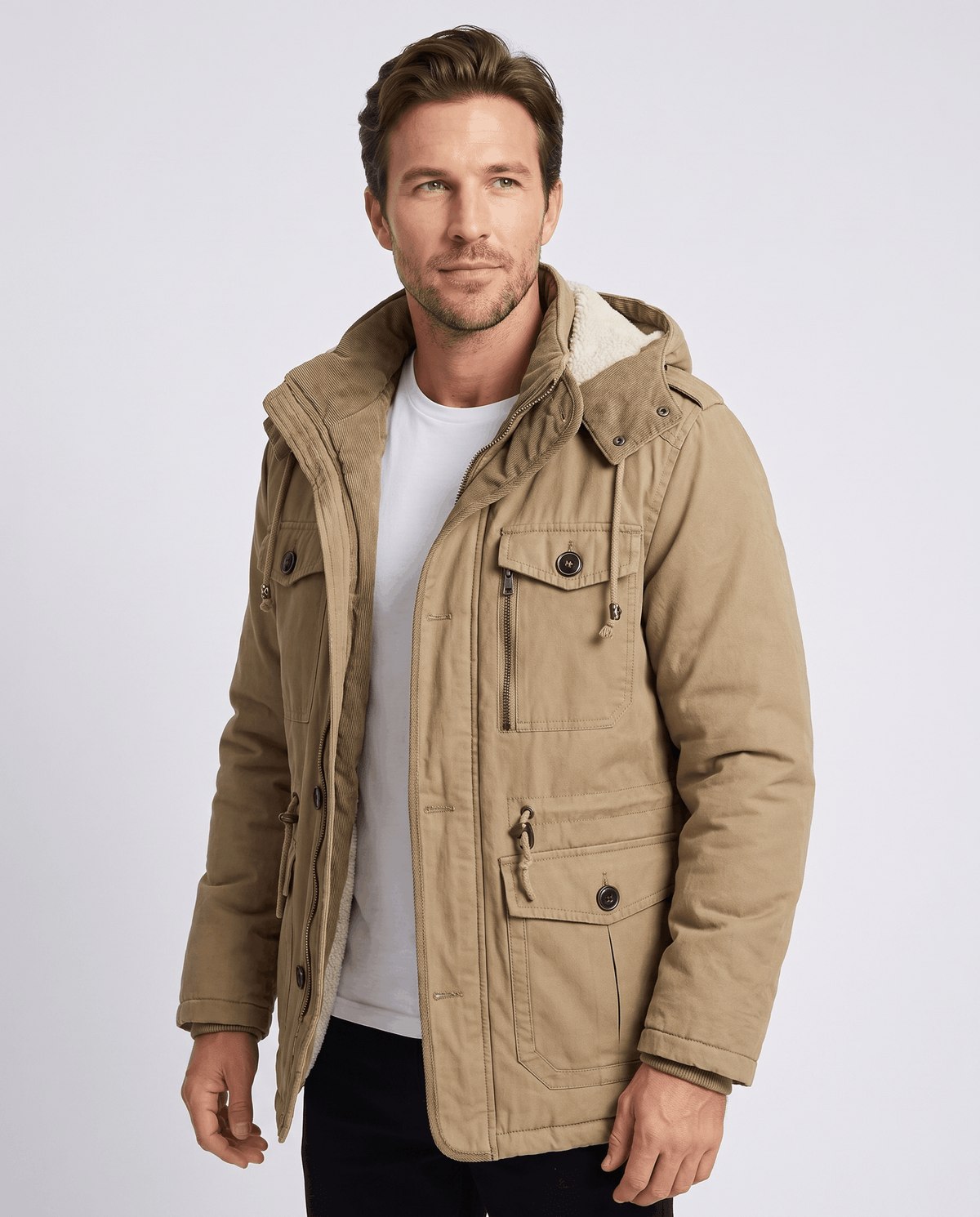 A man wearing a beige fleece-lined parka with a detachable hood, insulated design, zip front, and multiple utility pockets