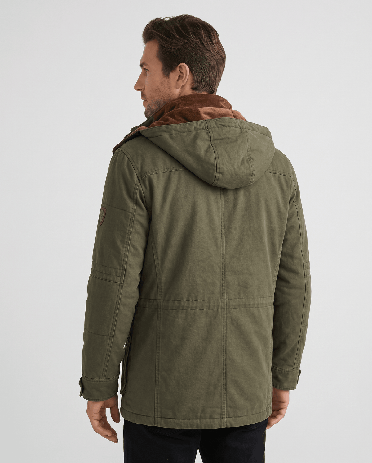 A man wearing an olive green fleece-lined parka with an insulated hood and weather-resistant outer shell, back view