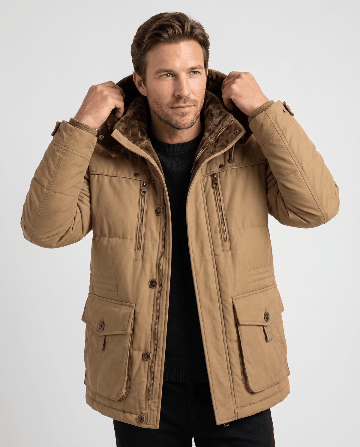 A man wearing a camel fleece-lined parka with an insulated hood and zip front, adjusting the hood