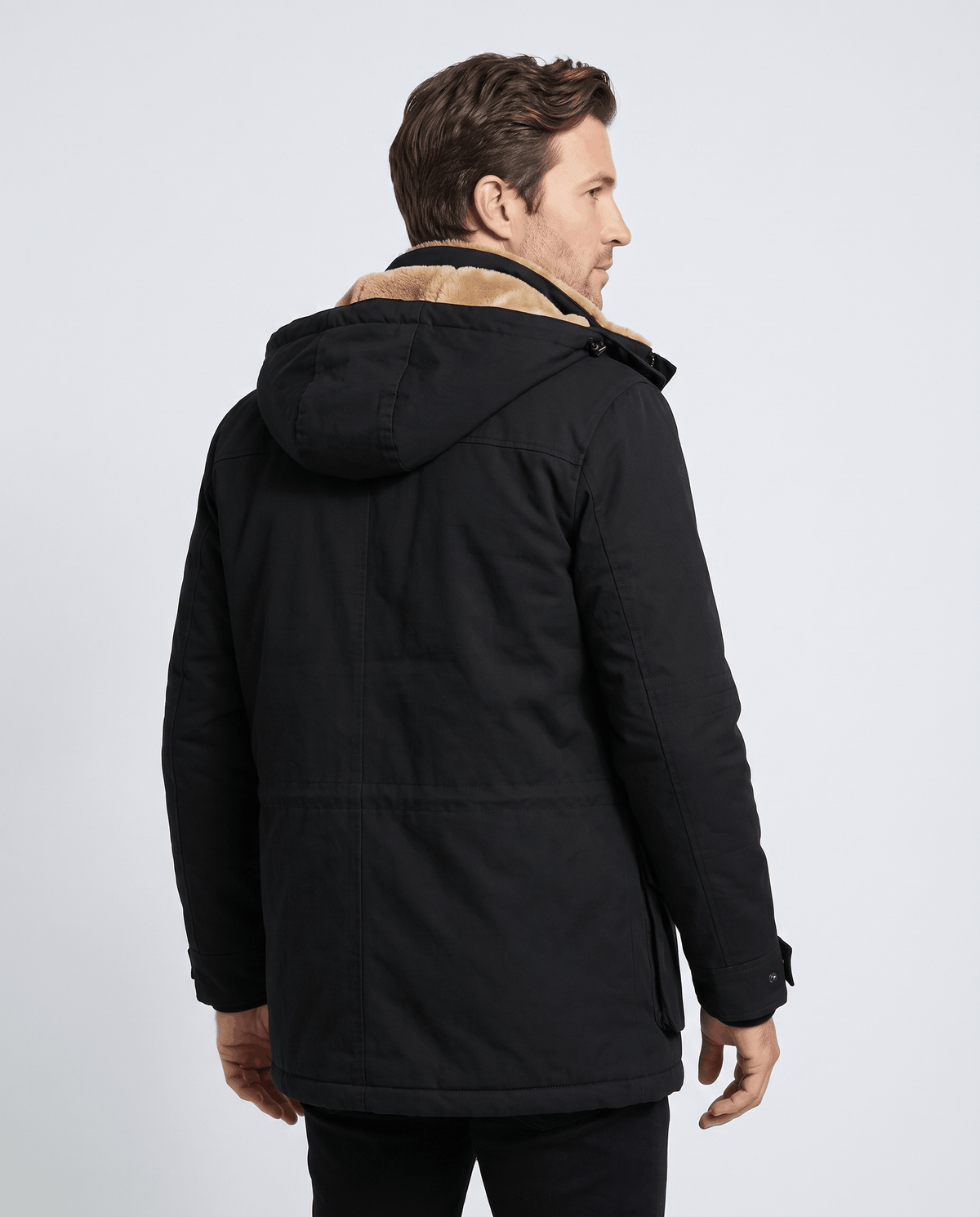A man wearing a black fleece-lined parka with an insulated hood and zip front, back view