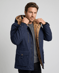 A man wearing a navy blue fleece-lined parka with an insulated design, hood, zip front, and weather-resistant outer shell