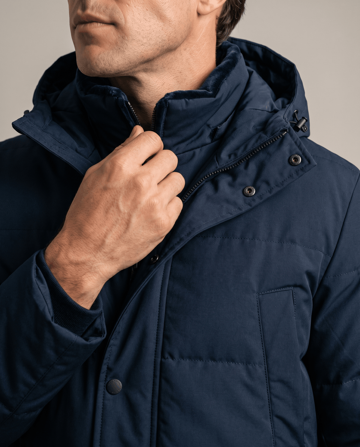 Close-up of a man wearing a navy blue fleece-lined winter jacket, showing the hood, collar, and full-zip front
