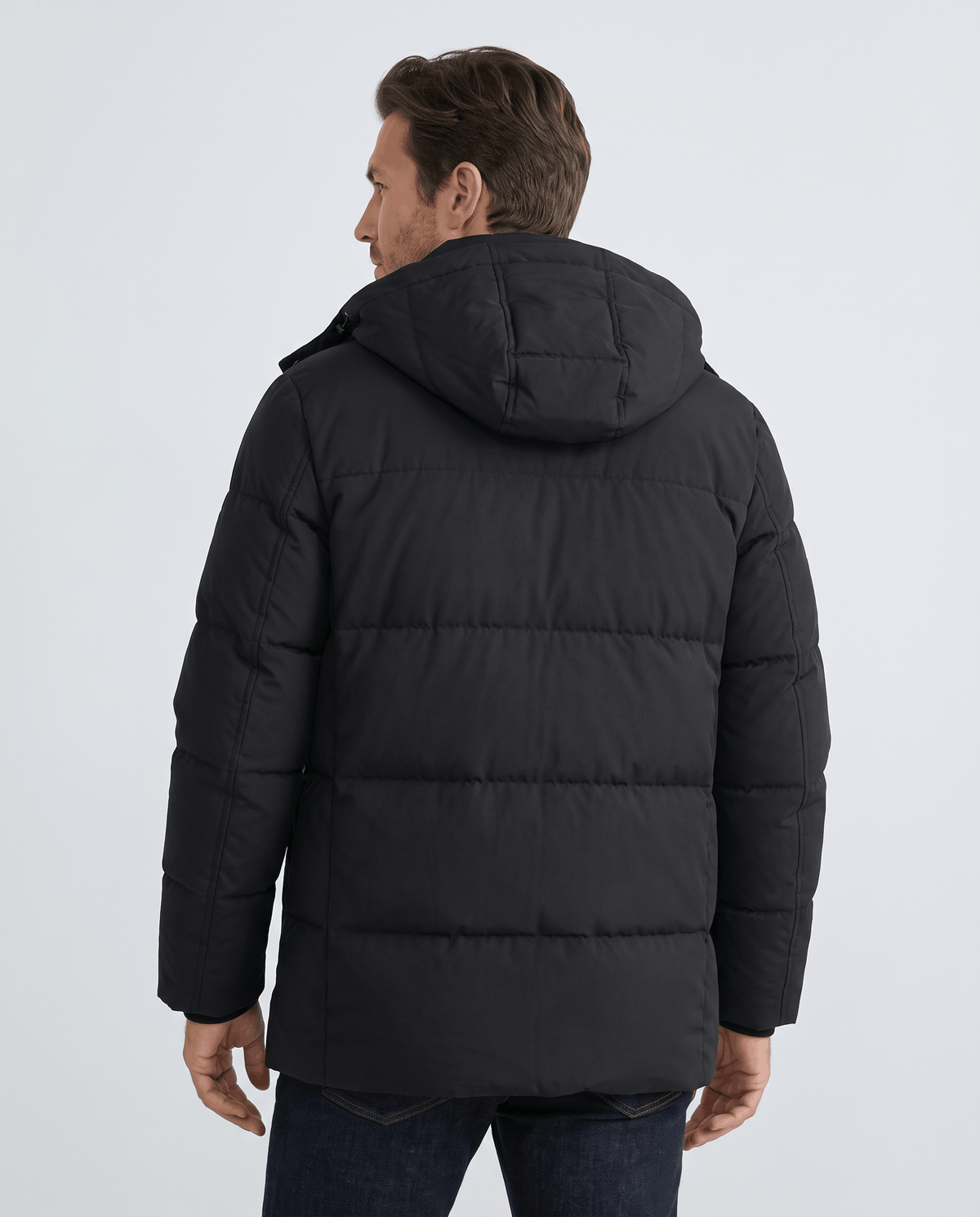 A man wearing a black fleece-lined winter jacket with a hood and full-zip front, shown from the back
