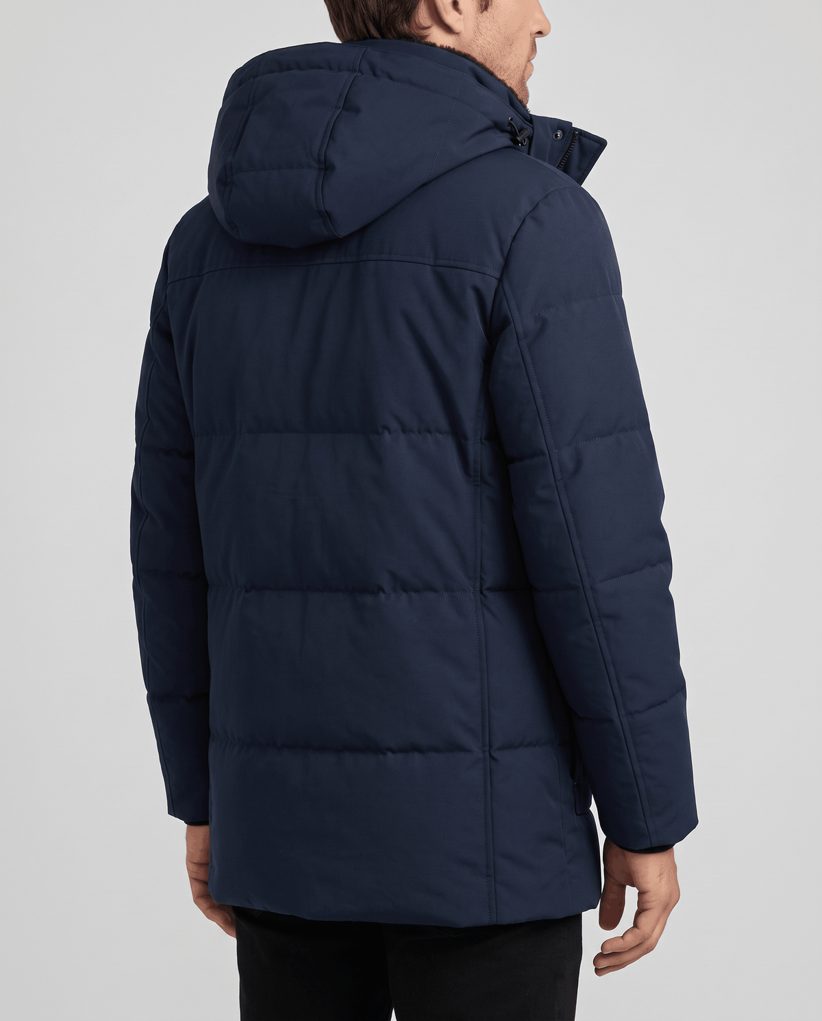 A man wearing a navy blue fleece-lined winter jacket with a hood and full-zip front, shown from the back