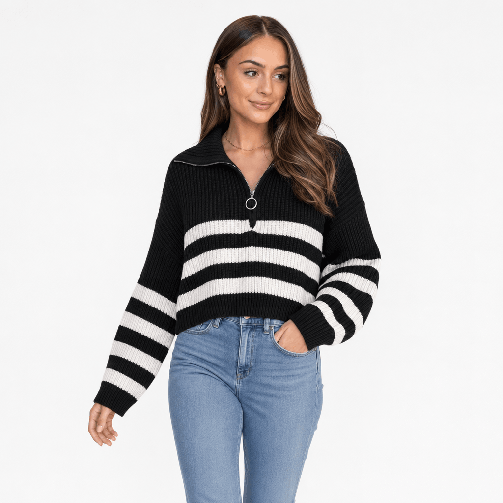 Female model wearing a black quarter-zip sweater with bold white horizontal stripes, paired with blue jeans.