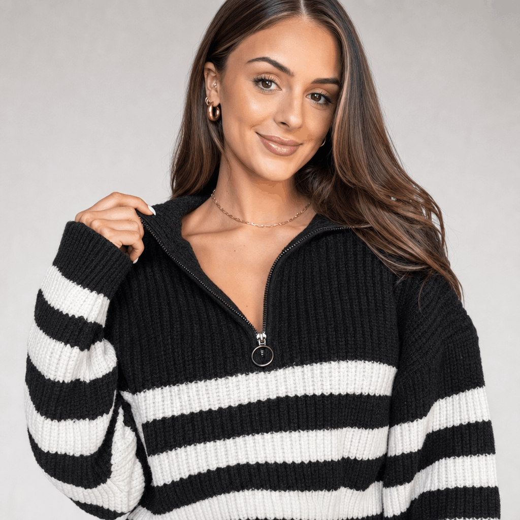 Close-up of the black striped quarter-zip sweater, highlighting the zipper collar and contrasting white stripe detail.