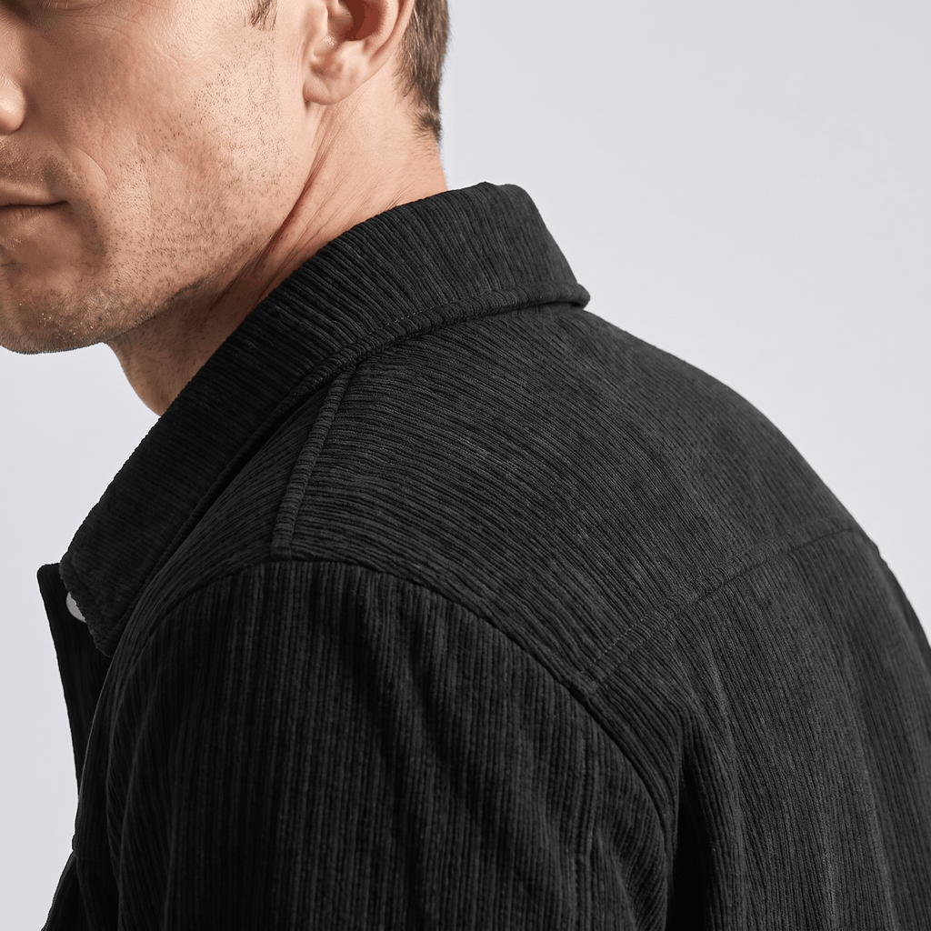Black corduroy trucker jacket with a structured collar and textured ribbed fabric worn by a man.