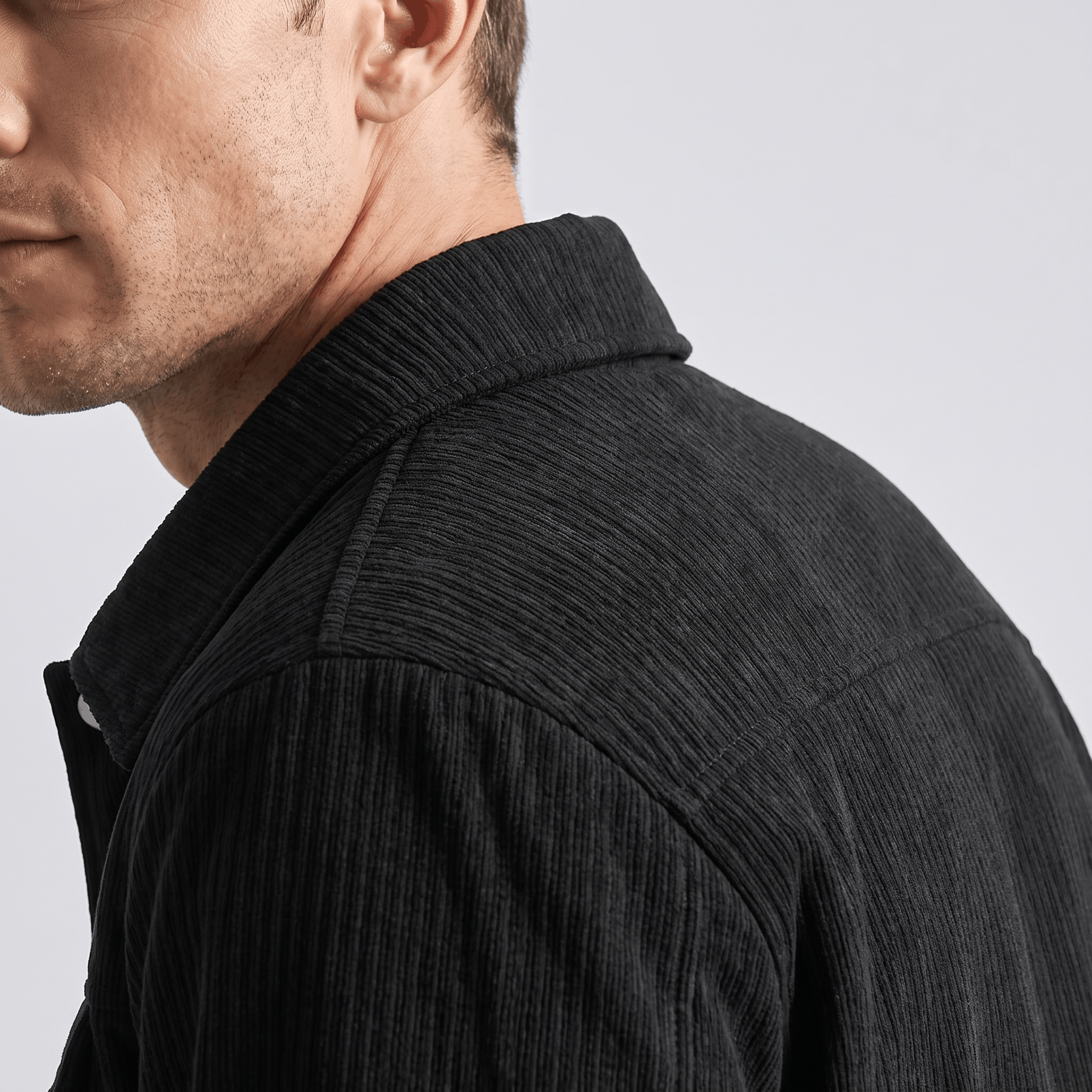 Black corduroy trucker jacket with a structured collar and textured ribbed fabric worn by a man.