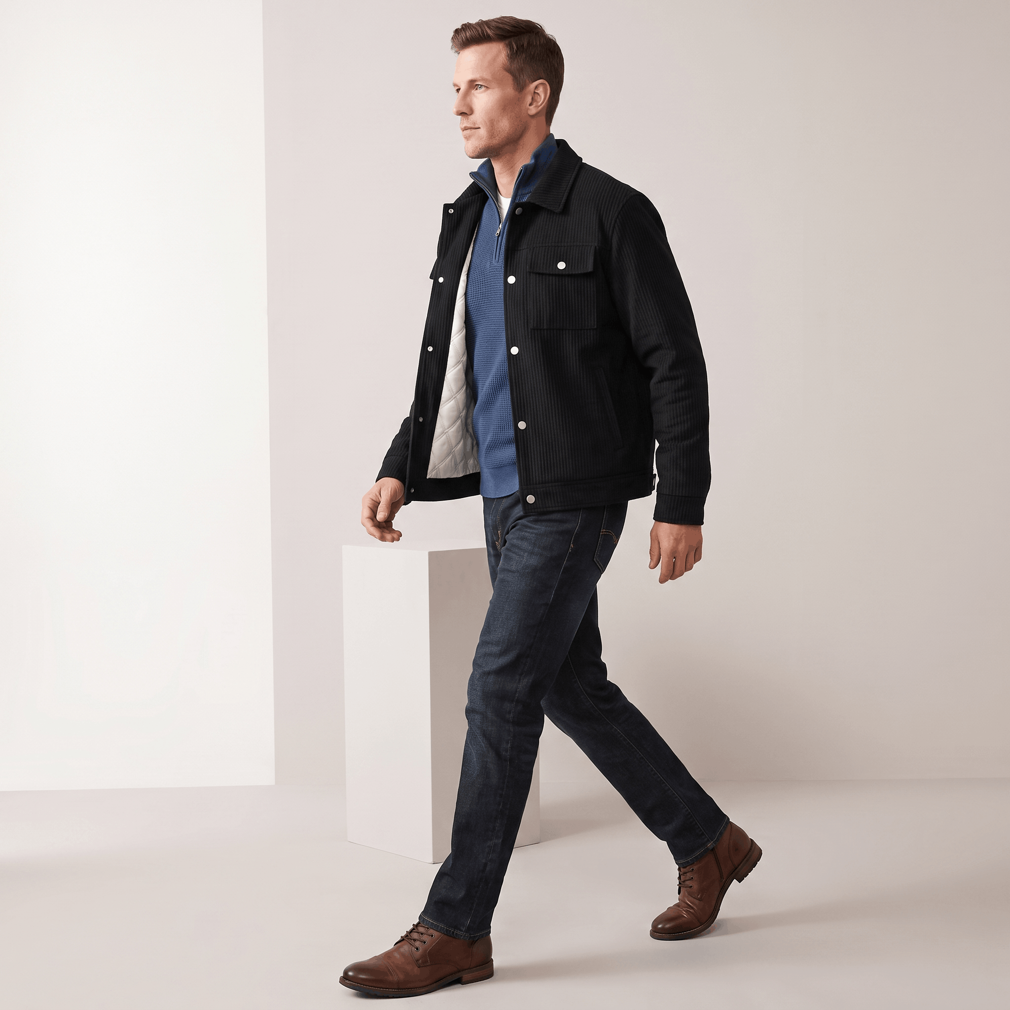 Black corduroy trucker jacket with snap-button front, dual chest pockets, and diamond-quilted lining worn over a blue sweater.